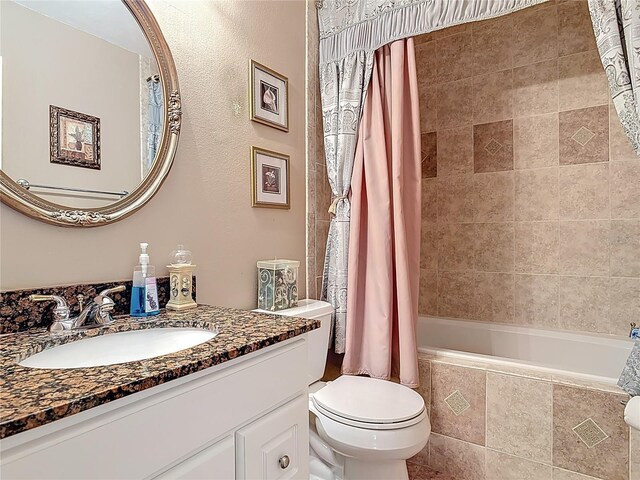 bathroom with toilet, vanity, and tiled shower / bath combo