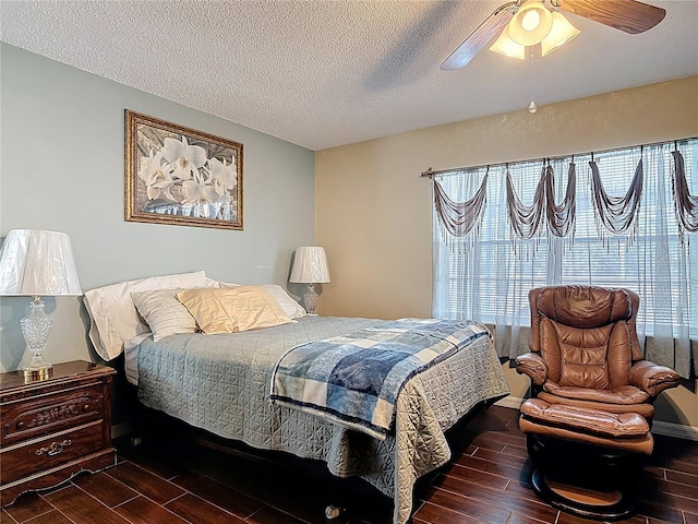 bedroom featuring a textured ceiling, multiple windows, and wood finish floors