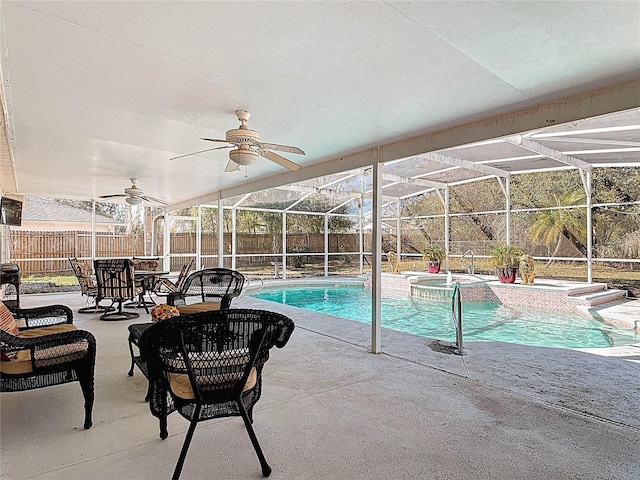 view of pool with glass enclosure, a patio, a fenced backyard, and a ceiling fan