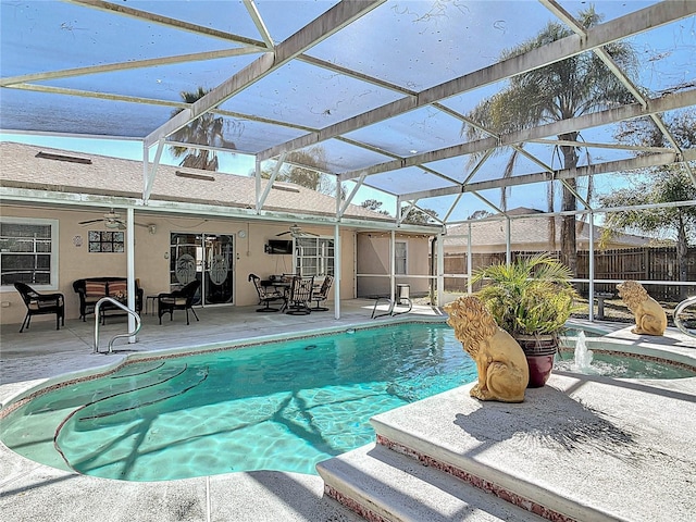 outdoor pool with a ceiling fan, glass enclosure, a patio area, and fence