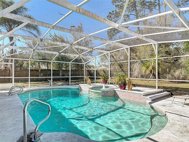 view of pool featuring a patio area, glass enclosure, a pool with connected hot tub, and a fenced backyard