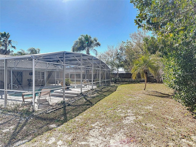 view of yard featuring an outdoor pool, a patio, a lanai, and fence