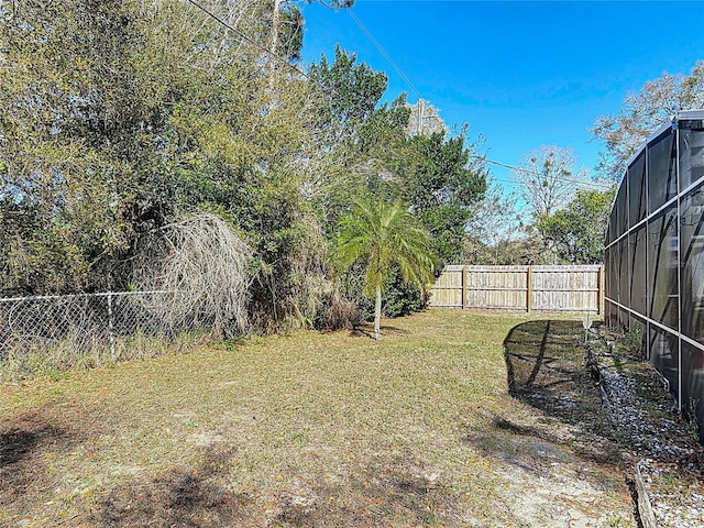 view of yard featuring glass enclosure and a fenced backyard