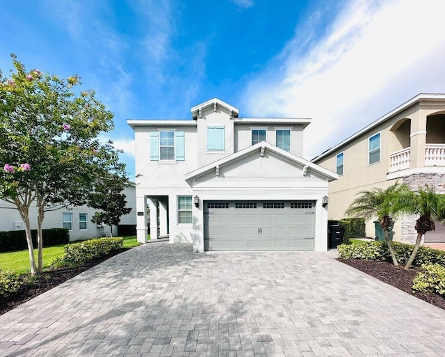 view of front facade featuring decorative driveway, an attached garage, and stucco siding