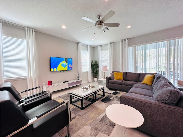 living area with a textured ceiling, ceiling fan, and recessed lighting