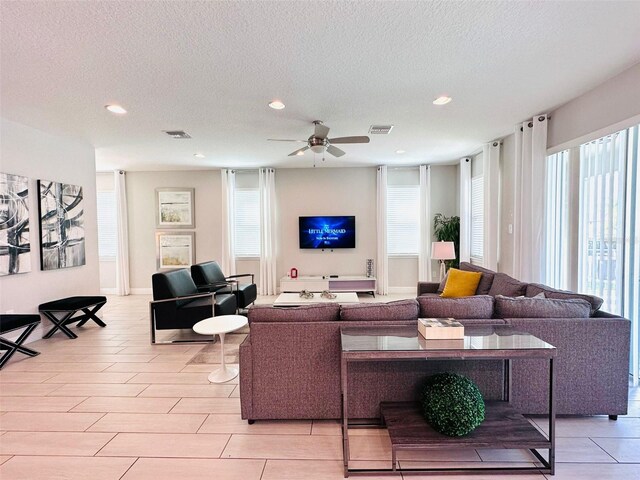 living room featuring recessed lighting, visible vents, ceiling fan, and a textured ceiling