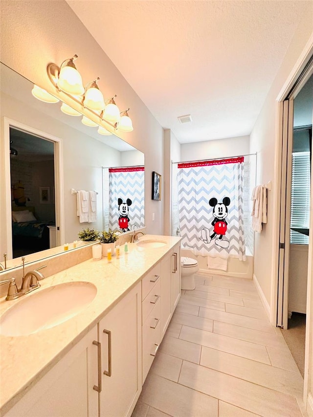 full bathroom with visible vents, double vanity, a sink, and toilet