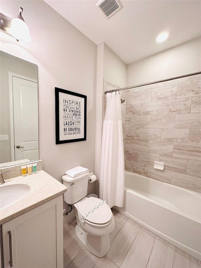 bathroom featuring visible vents, shower / bathtub combination with curtain, toilet, vanity, and a textured ceiling