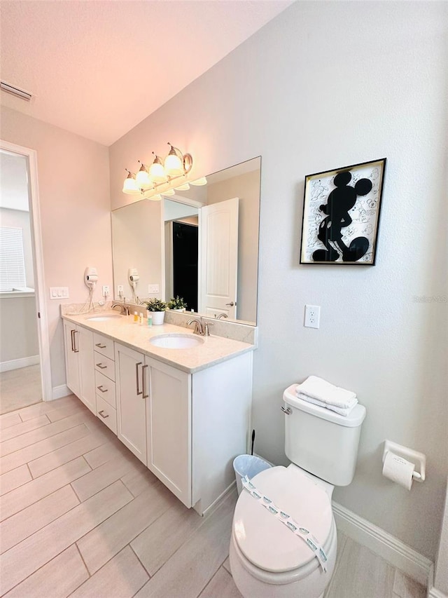 bathroom with double vanity, a sink, visible vents, and baseboards