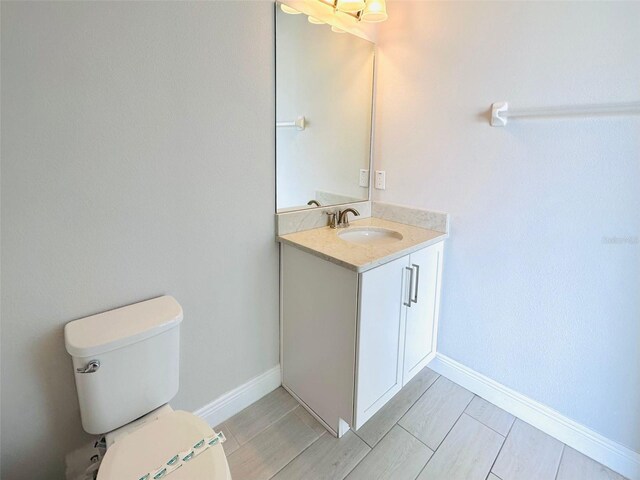 bathroom with toilet, baseboards, and vanity