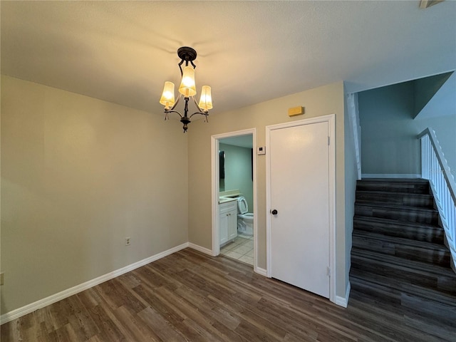 interior space featuring stairs, a chandelier, dark wood-style floors, and baseboards