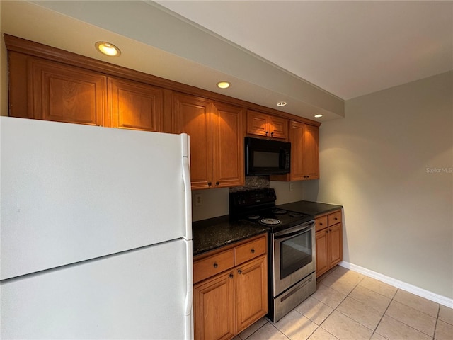 kitchen featuring brown cabinets, freestanding refrigerator, black microwave, and stainless steel range with electric cooktop