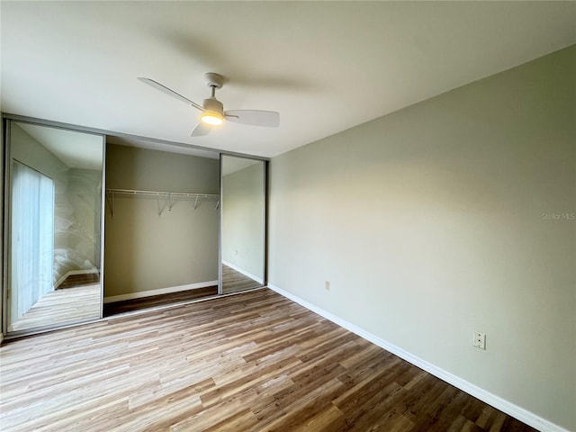 unfurnished bedroom with ceiling fan, a closet, wood finished floors, and baseboards