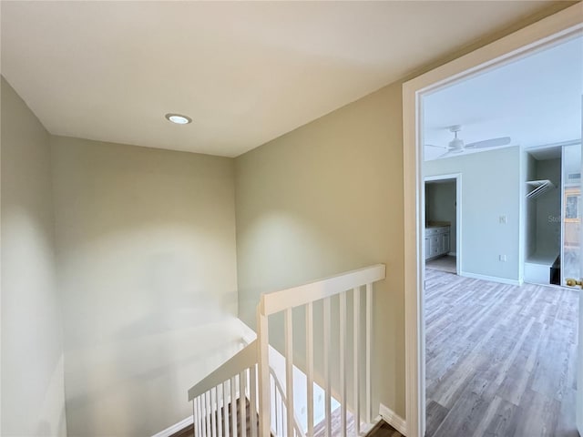 hallway featuring baseboards, an upstairs landing, and wood finished floors