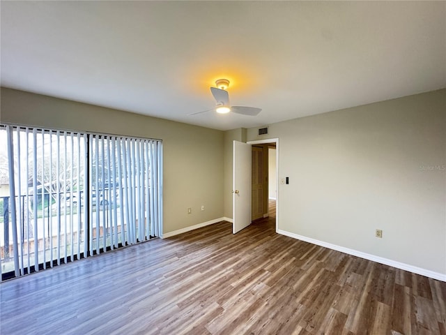 unfurnished room with a ceiling fan, visible vents, baseboards, and wood finished floors