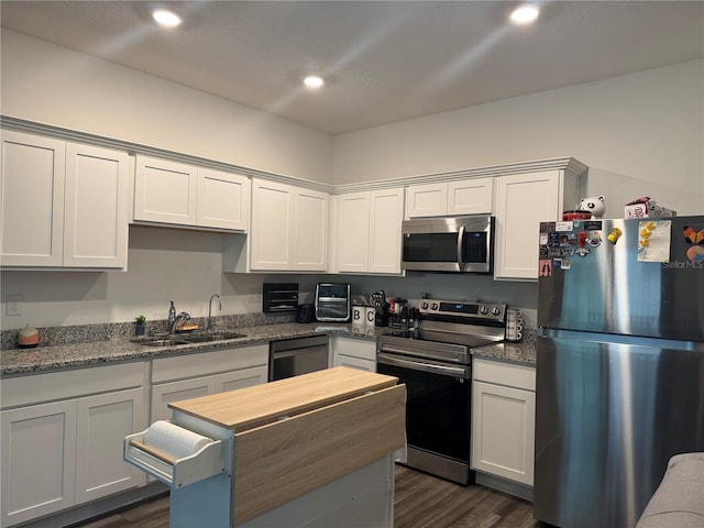 kitchen with dark wood finished floors, recessed lighting, a sink, appliances with stainless steel finishes, and white cabinetry