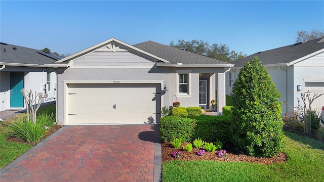 ranch-style house featuring decorative driveway, a garage, roof with shingles, and stucco siding