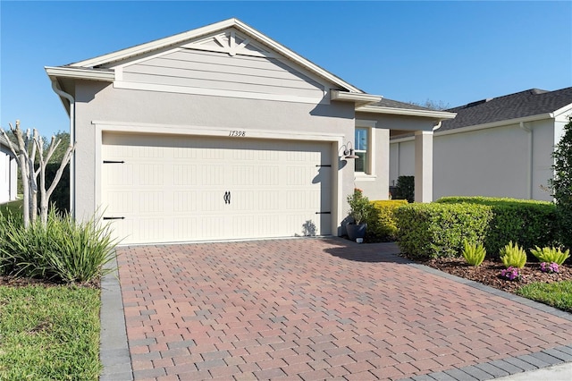 single story home with decorative driveway, an attached garage, and stucco siding