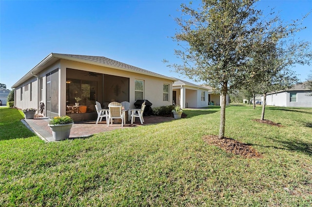 rear view of house with a patio area, stucco siding, a lawn, and a sunroom