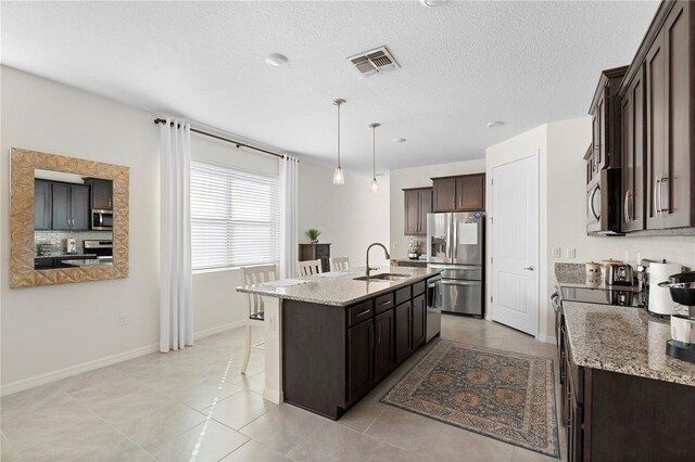 kitchen with visible vents, dark brown cabinets, a kitchen bar, appliances with stainless steel finishes, and a sink