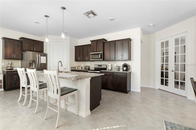 kitchen featuring visible vents, a sink, a kitchen breakfast bar, french doors, and appliances with stainless steel finishes