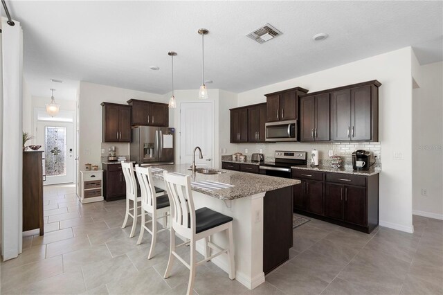 kitchen featuring visible vents, a sink, backsplash, stainless steel appliances, and dark brown cabinetry