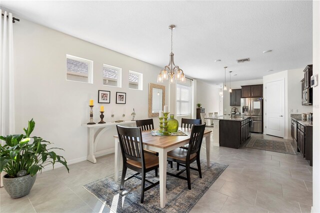 dining area featuring light tile patterned floors, visible vents, baseboards, and a chandelier