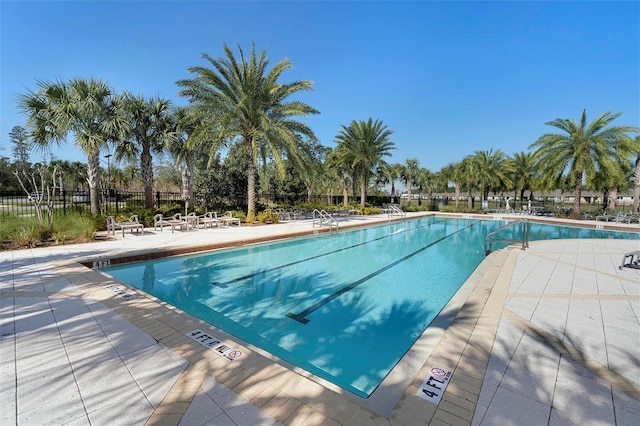 community pool with a patio and fence