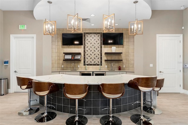 bar featuring decorative light fixtures, decorative backsplash, visible vents, and light wood finished floors