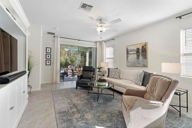 living area featuring a wealth of natural light, visible vents, baseboards, and a ceiling fan