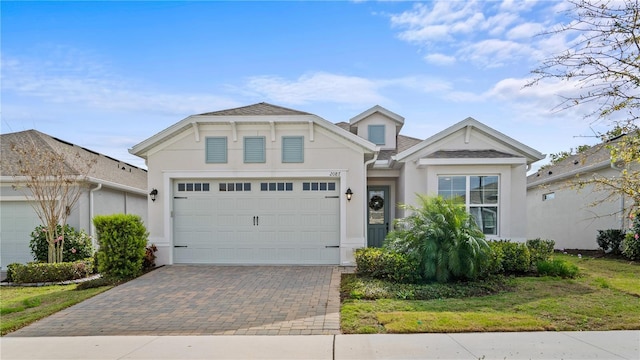 view of front facade with decorative driveway, an attached garage, and stucco siding