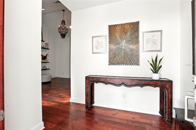 hallway with a notable chandelier, baseboards, and wood finished floors