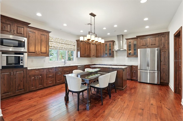 kitchen featuring appliances with stainless steel finishes, dark wood finished floors, decorative backsplash, and wall chimney exhaust hood