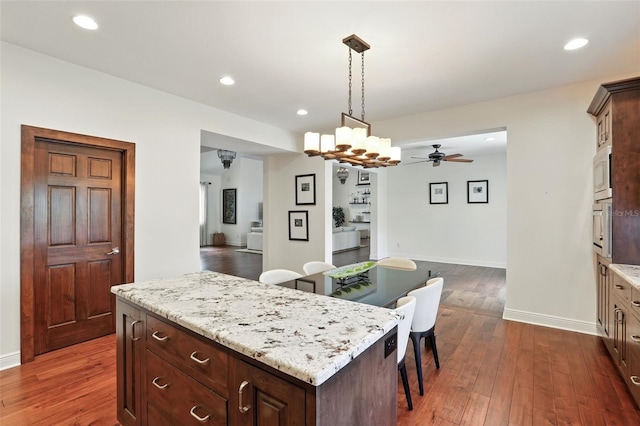 kitchen with a center island, dark wood finished floors, recessed lighting, hanging light fixtures, and wall oven