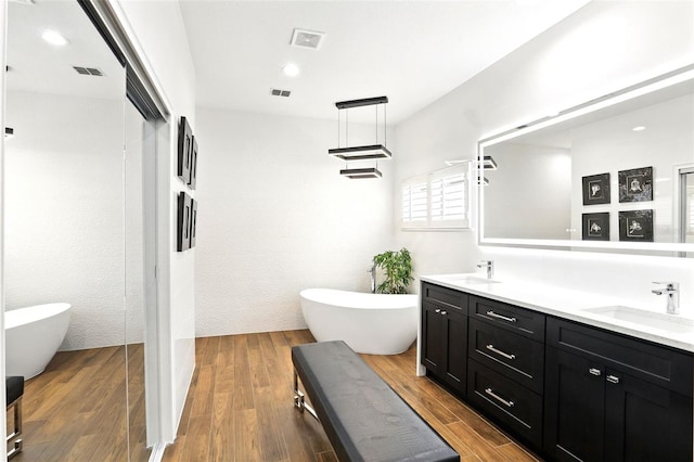 bathroom featuring double vanity, visible vents, a sink, and wood finished floors