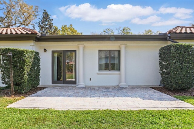 rear view of house with a patio area, a tile roof, and stucco siding