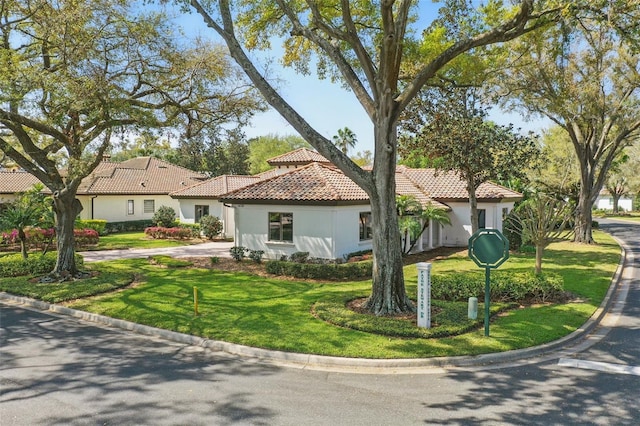 mediterranean / spanish-style house featuring a tiled roof, a front lawn, and stucco siding