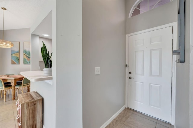 foyer featuring light tile patterned flooring and baseboards