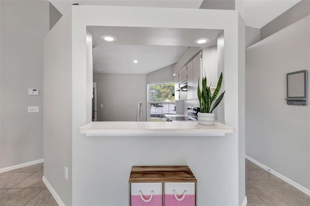 kitchen with baseboards, stainless steel electric range, light tile patterned flooring, and light countertops