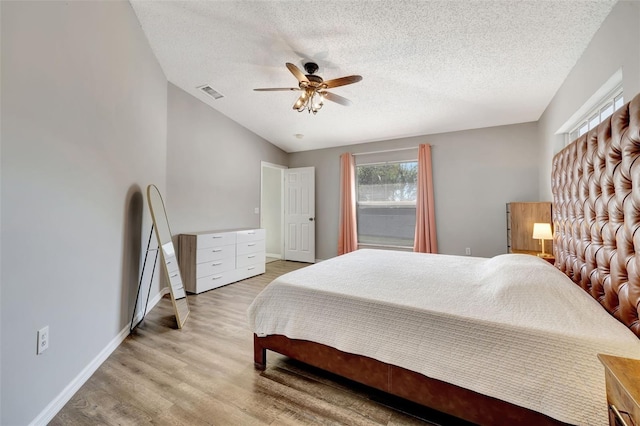 bedroom featuring visible vents, a textured ceiling, wood finished floors, baseboards, and ceiling fan