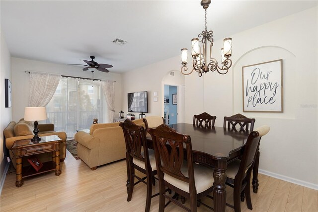 dining room with visible vents, baseboards, light wood-type flooring, ceiling fan with notable chandelier, and arched walkways