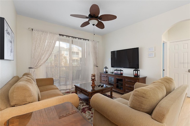 living room featuring arched walkways, wood finished floors, and a ceiling fan