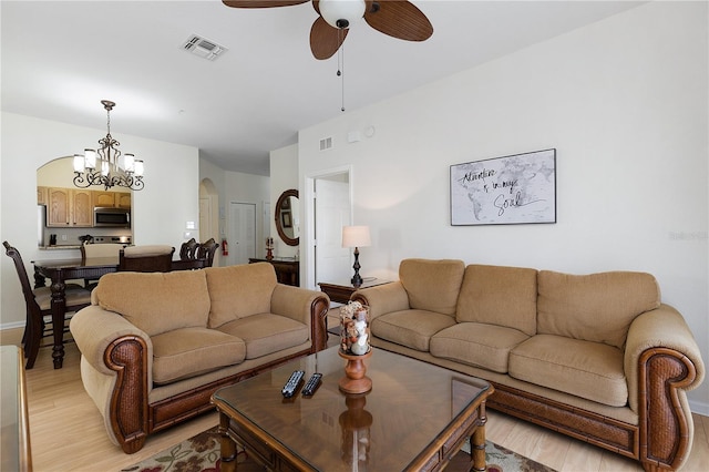 living area featuring light wood-type flooring, visible vents, arched walkways, and ceiling fan