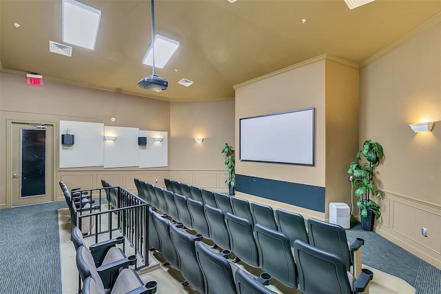 carpeted home theater featuring a decorative wall, ornamental molding, visible vents, and wainscoting