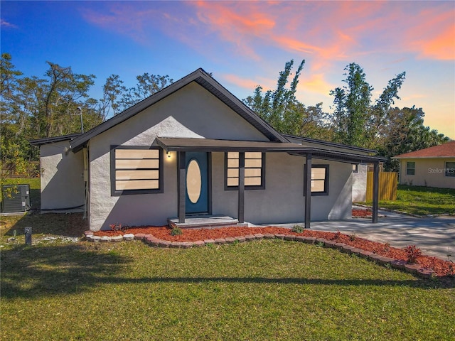 view of front of house with cooling unit, a yard, driveway, and stucco siding