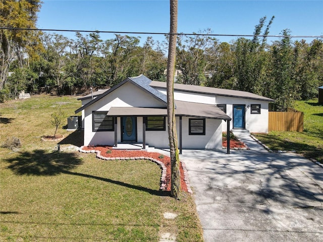 view of front of property with driveway, a front yard, fence, and stucco siding