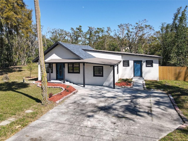 mid-century modern home with driveway, fence, a front lawn, and stucco siding