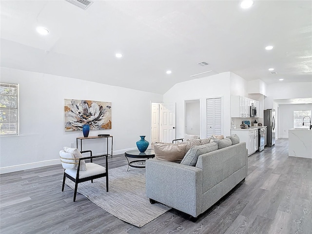 living area with recessed lighting, visible vents, vaulted ceiling, wood finished floors, and baseboards