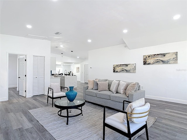 living room featuring recessed lighting, vaulted ceiling, baseboards, and wood finished floors