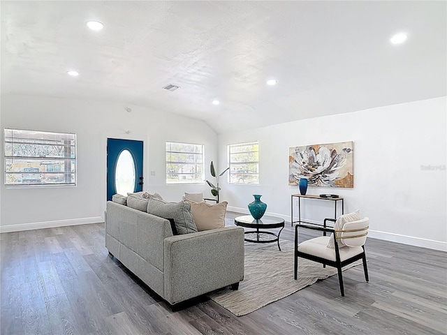 living room featuring visible vents, baseboards, vaulted ceiling, and wood finished floors